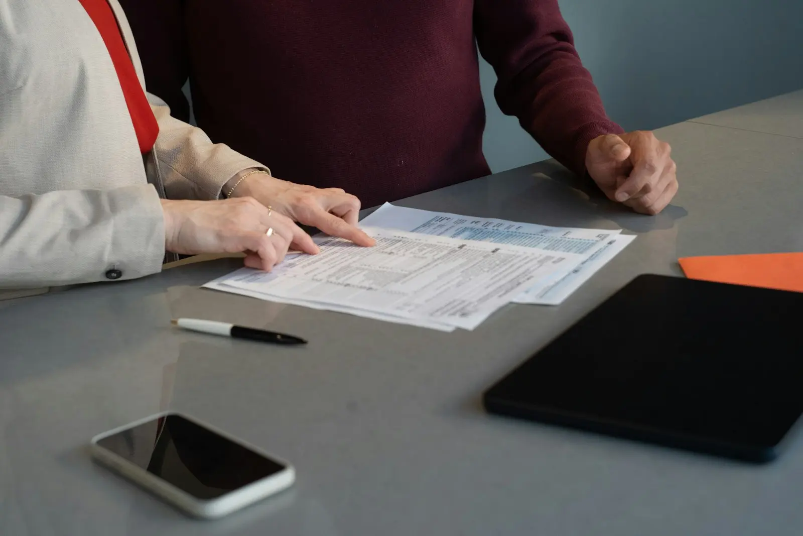 Avocat et client consultant un document juridique sur un bureau avec smartphone et tablette