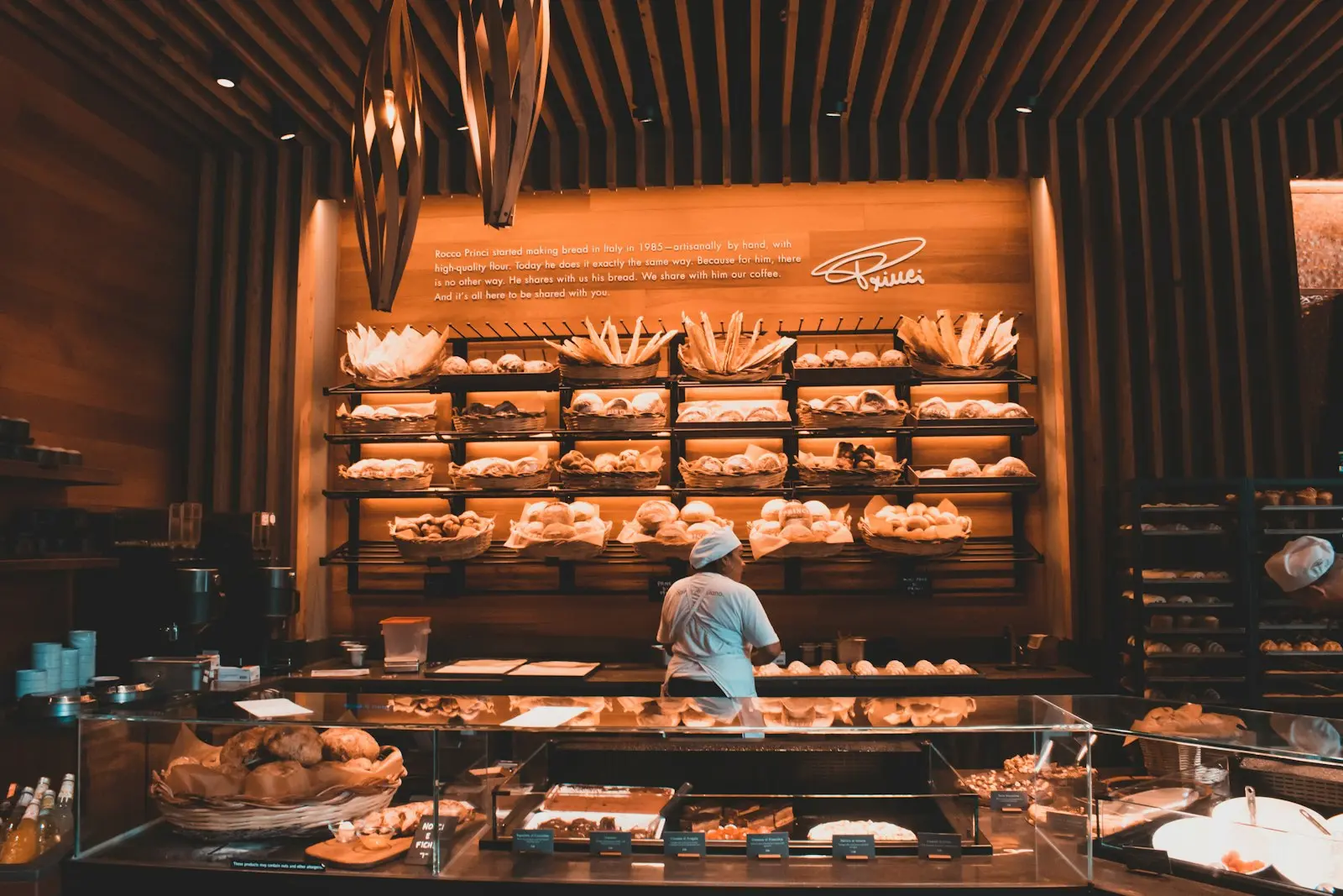 Boulanger travaillant devant de grands étals de pains et corbeilles dans une boulangerie design