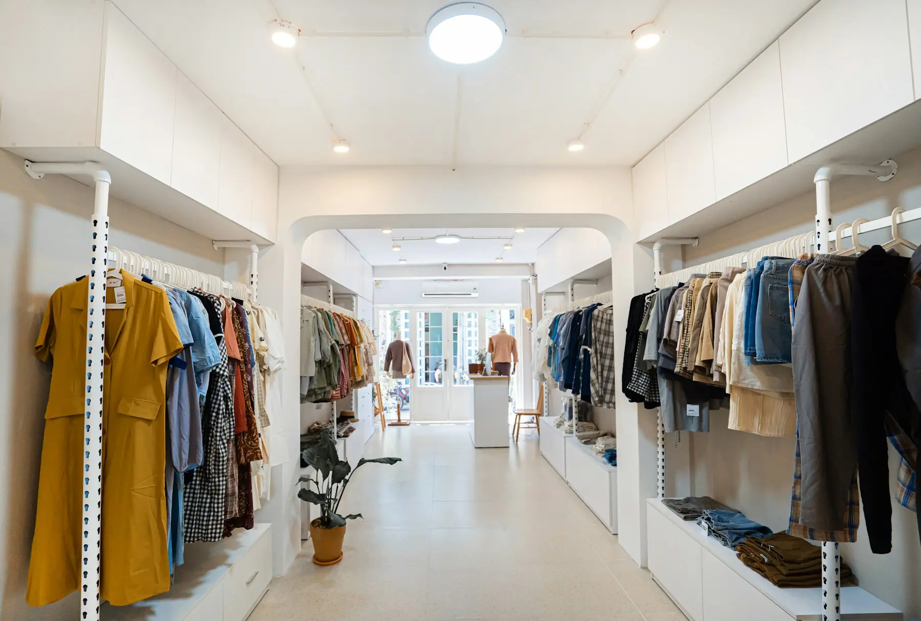 Allée centrale d'une boutique de vêtements avec rayonnages symétriques et mannequin en vitrine
