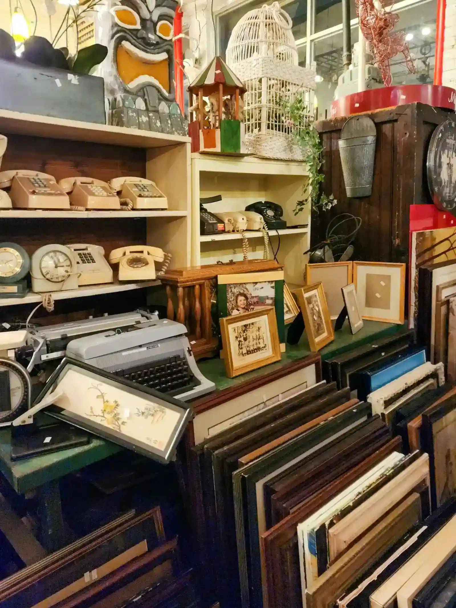 Sélection d'objets vintage en brocante : téléphones anciens, horloges, machine à écrire et cadres