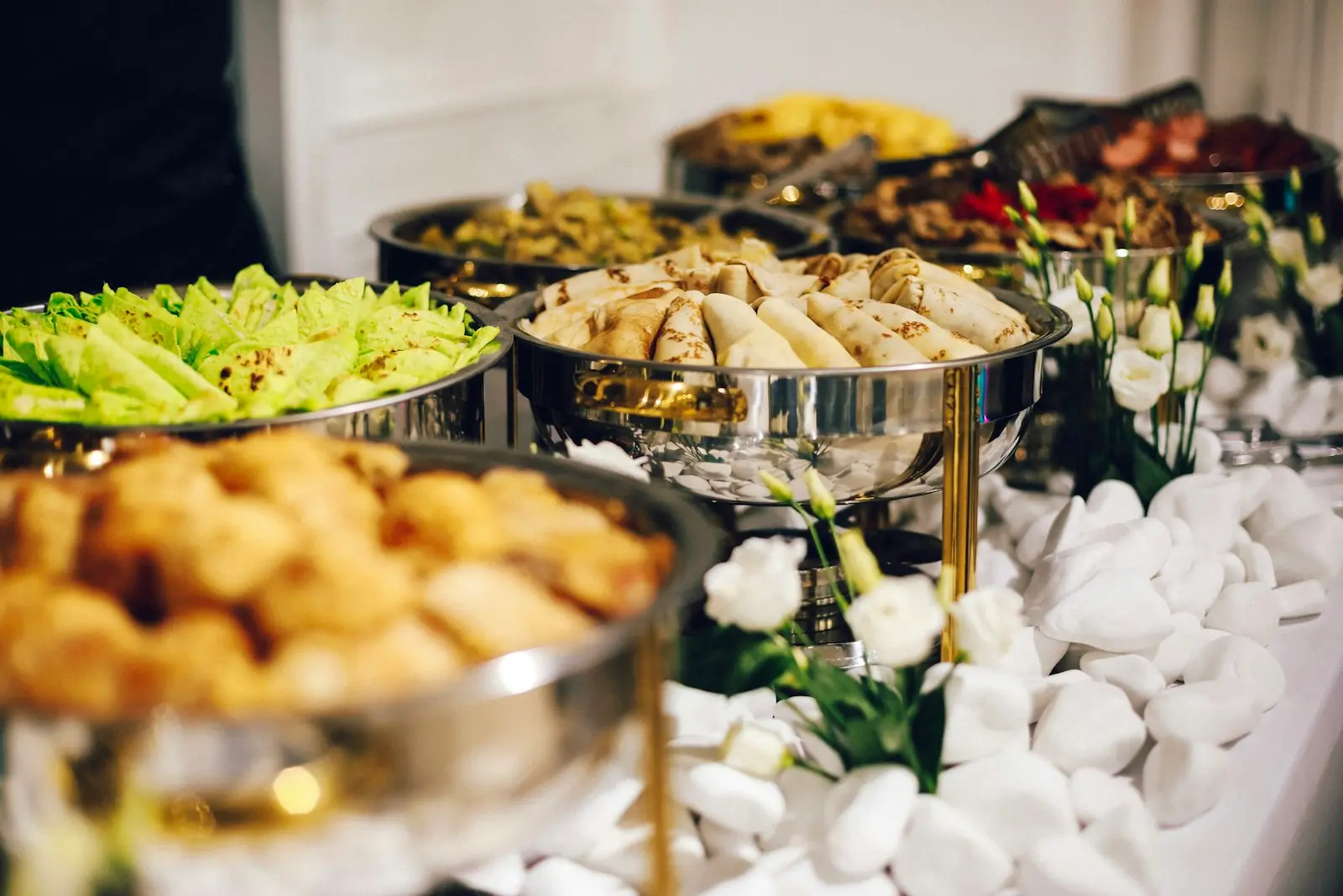Buffet traiteur raffiné avec plats chauds, salades et décoration florale pour réception