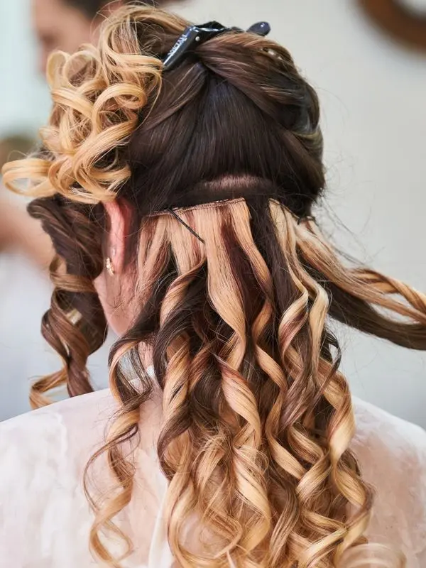 Vue arrière de longues boucles blondes et brunes coiffées en salon de beauté