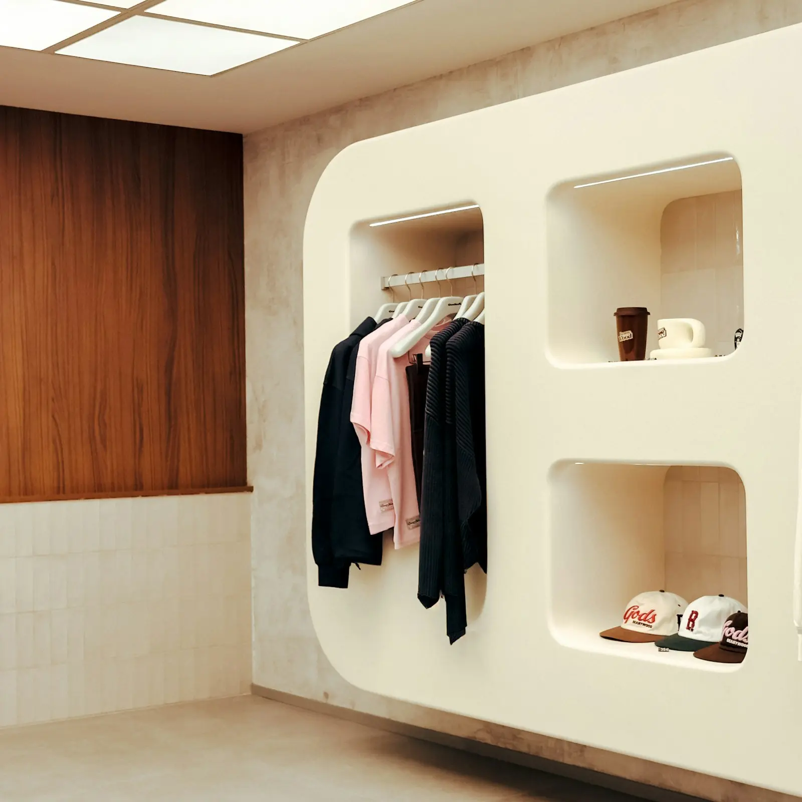 Niches murales design exposant vêtements suspendus, tasses et casquettes dans un concept store