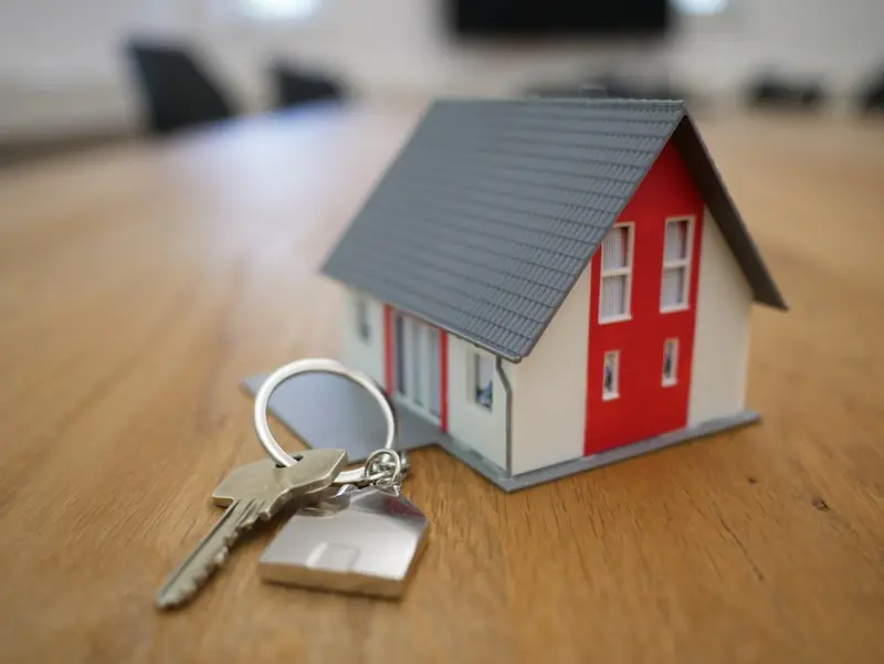 Maison miniature et trousseau de clés symbolisant les services d'un agent immobilier