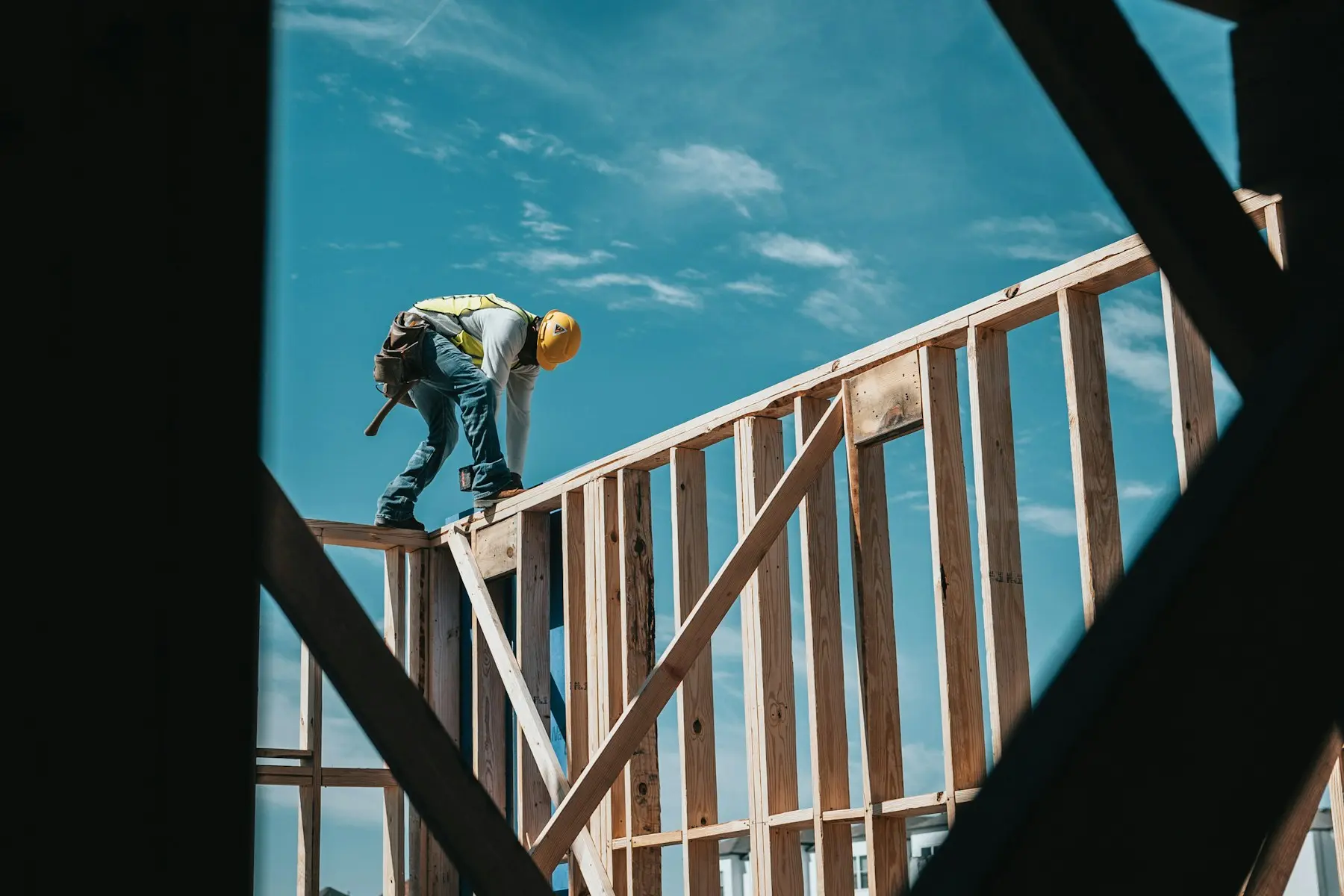 Charpentier grimpant sur l'ossature bois d'une maison en cours de construction