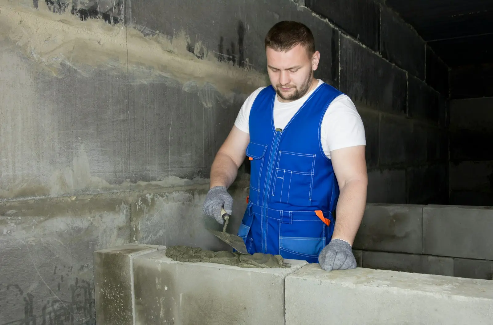 Maçon appliquant du mortier à la truelle pour monter un mur de parpaings
