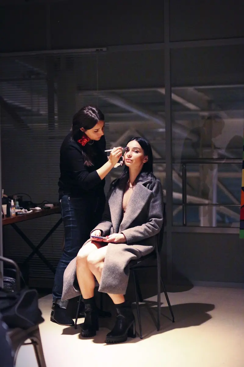 Maquilleuse professionnelle appliquant un maquillage à une cliente en coulisses - création site internet maquilleuse