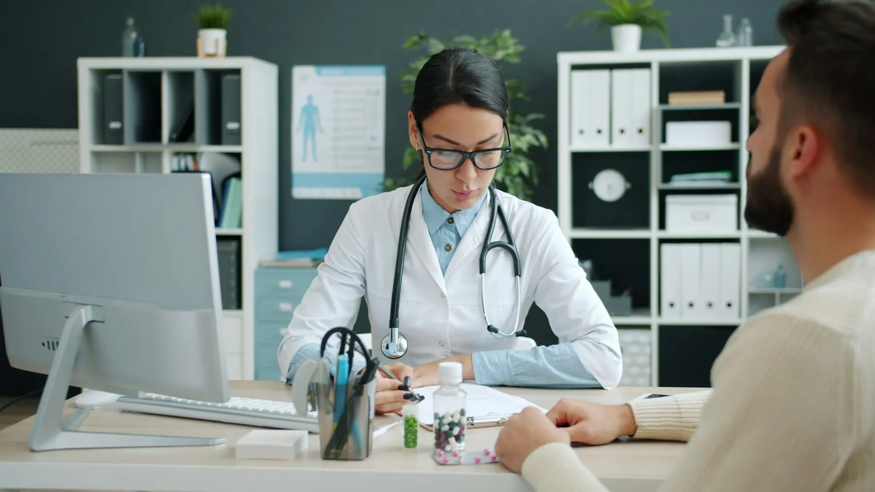 Médecin généraliste en blouse blanche consultant un patient à son bureau