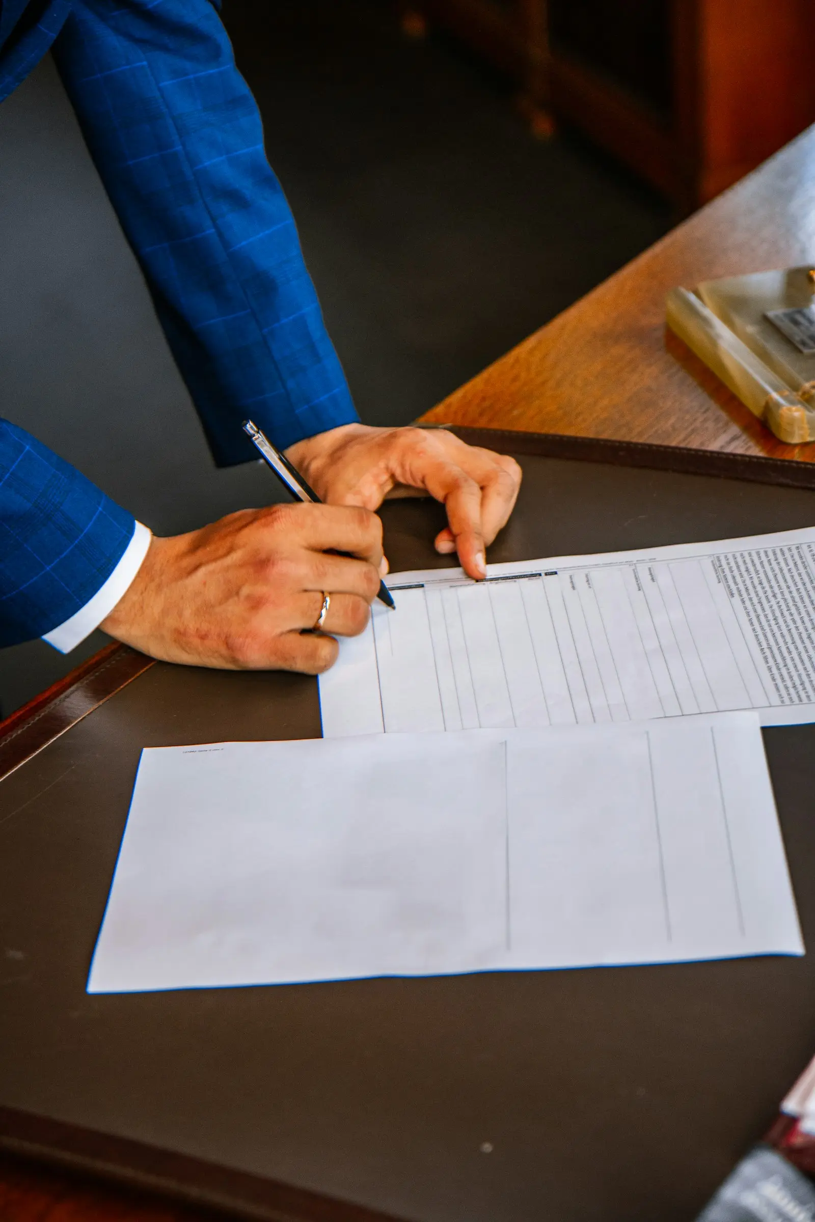 Notaire en costume signant un acte authentique sur un bureau en bois