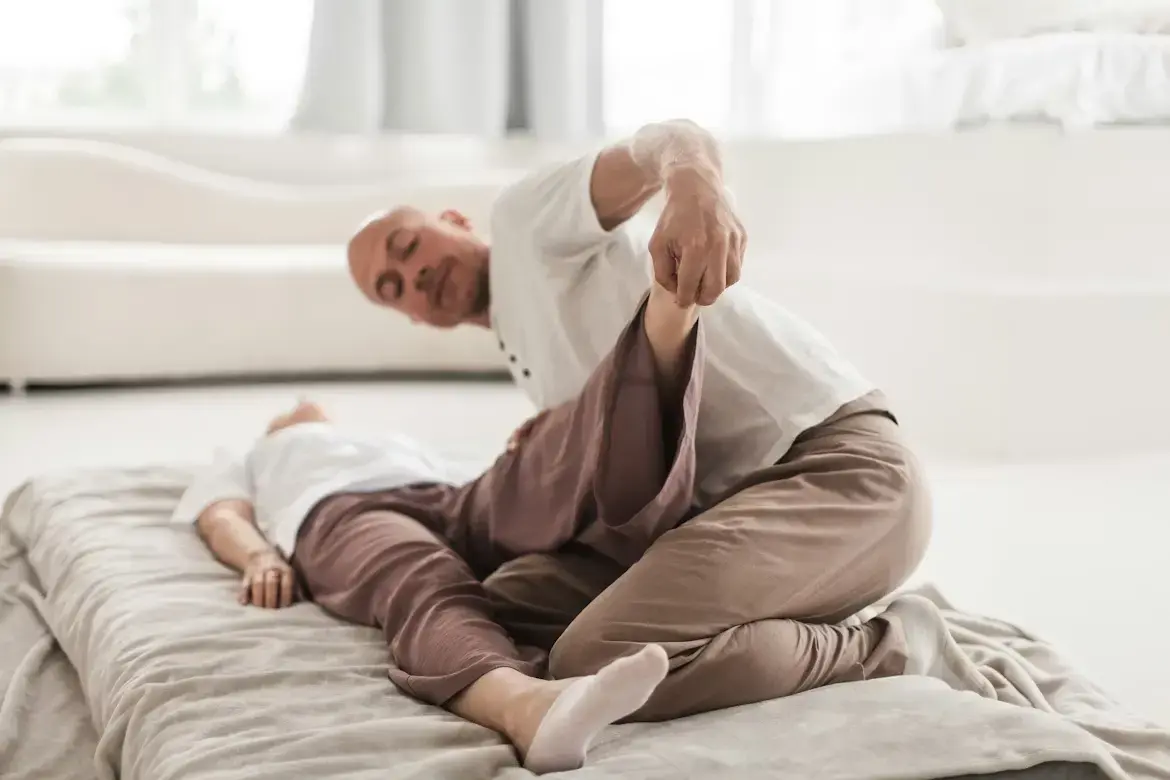 Ostéopathe manipulant la jambe d'un patient allongé dans un cabinet lumineux