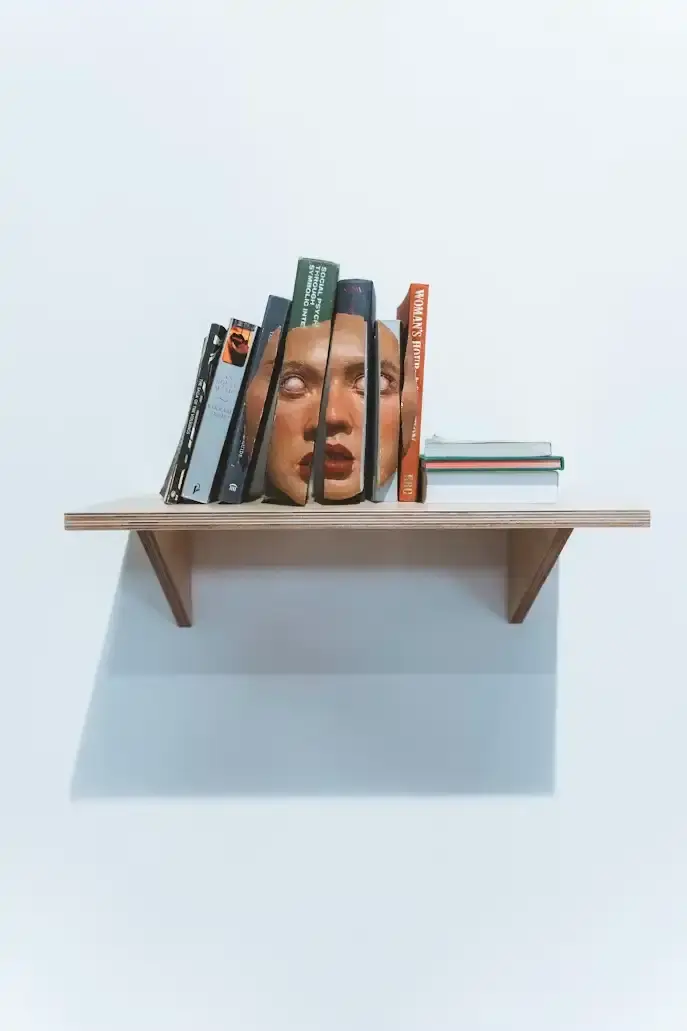 Illustration symbolique de la psychologie : visage fragmenté entre les livres d'une bibliothèque
