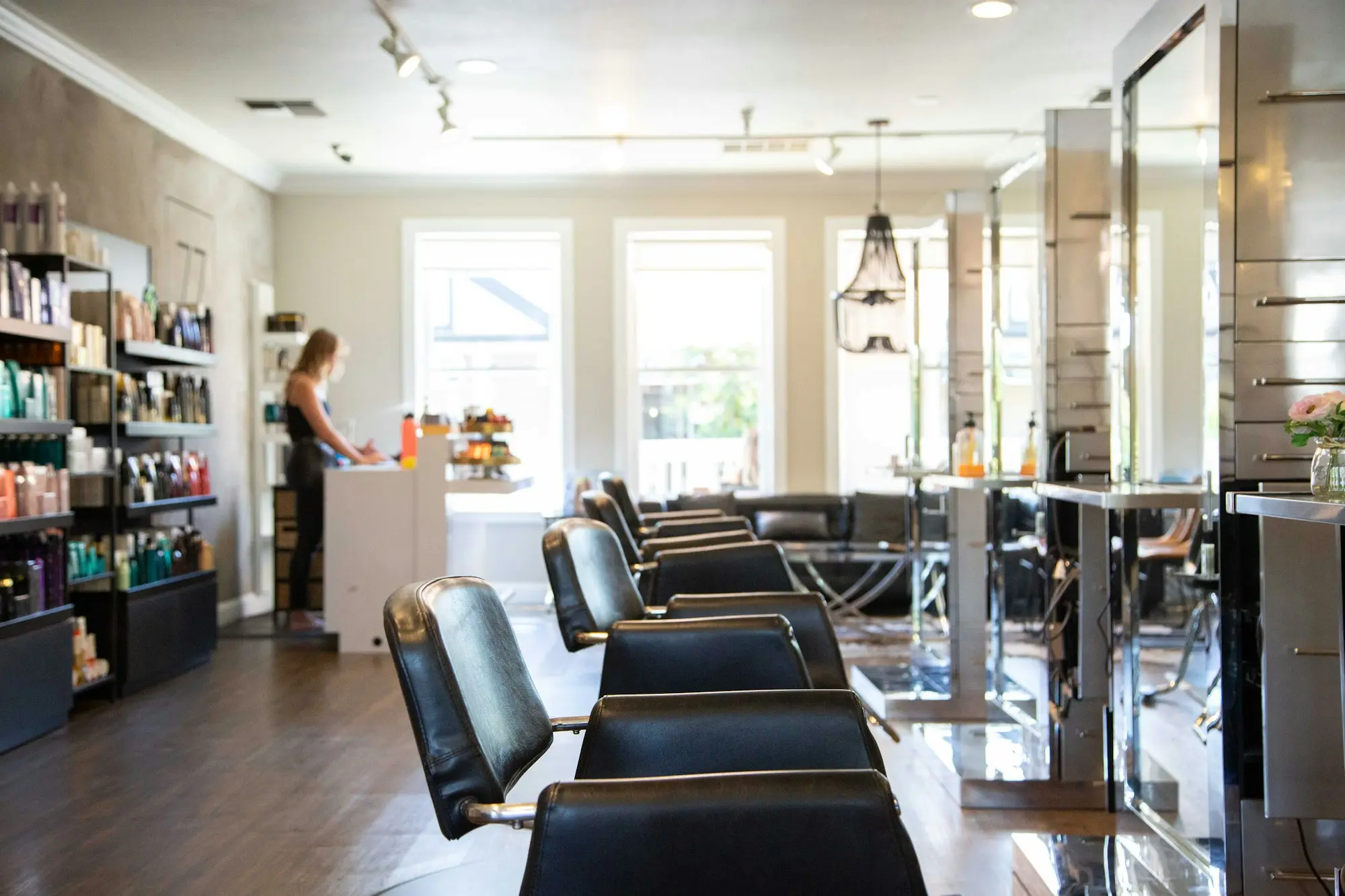 Salon de coiffure moderne avec rangée de fauteuils noirs et produits capillaires - création site internet salon