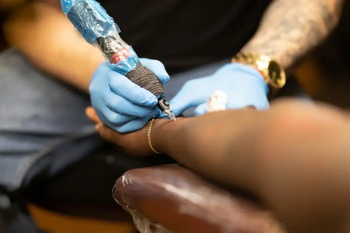 Création de site internet pour tatoueur : gros plan sur une main gantée tenant un dermographe
