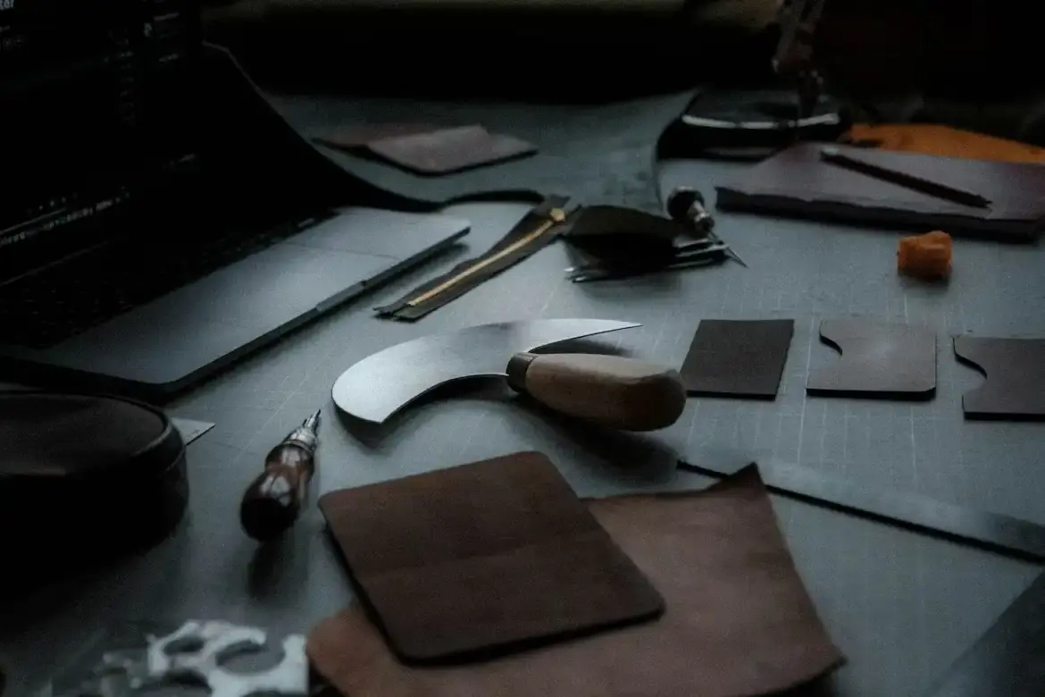 Établi d'atelier de bijoutier artisan : couteau de coupe, chutes de cuir et outils de précision
