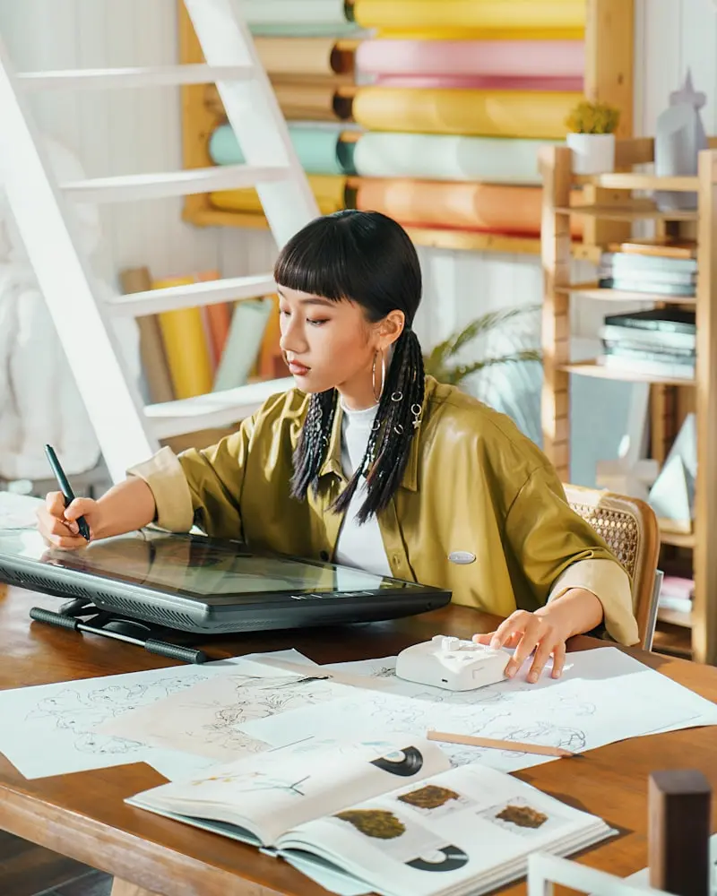 Illustratrice dessinant une illustration numérique sur tablette graphique dans son atelier