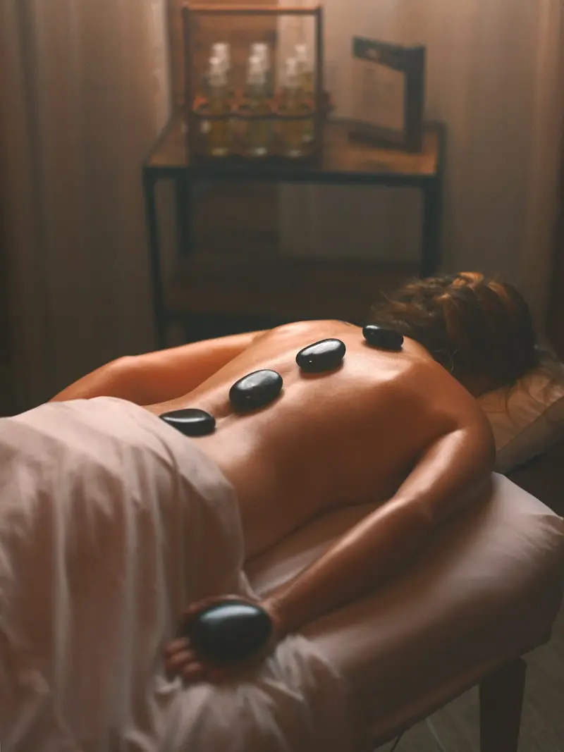 Massage aux pierres chaudes posées sur le dos dans une ambiance spa tamisée