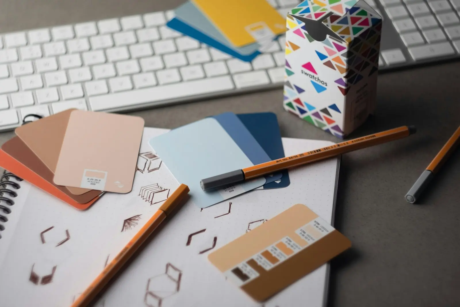 Bureau de graphiste avec nuanciers de couleurs, crayons et carnet de croquis géométriques