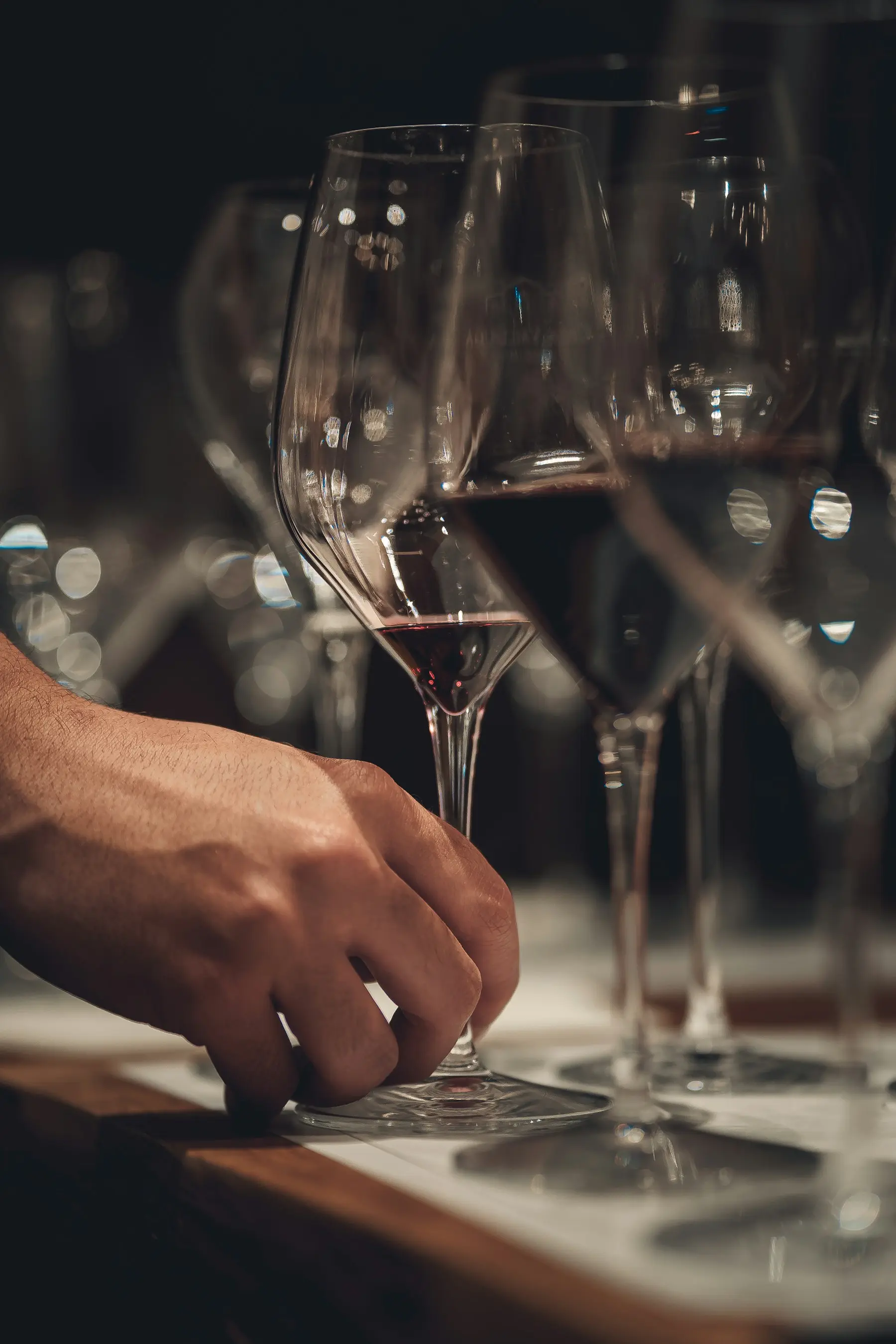 Main saisissant un verre de vin rouge parmi plusieurs échantillons lors d'une analyse d'œnologue