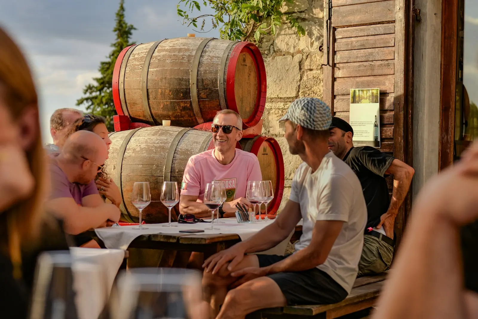 Groupe d'amis partageant une dégustation de vin en terrasse près des barriques d'un domaine