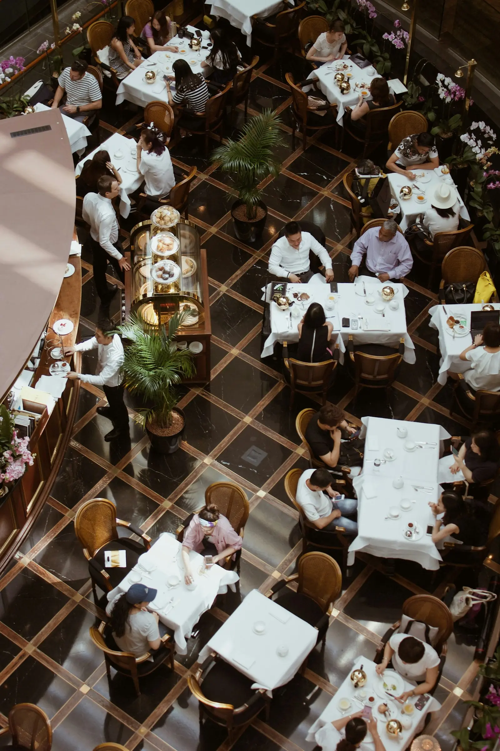 Vue aérienne d'une salle de restaurant gastronomique animée avec tables dressées et serveurs