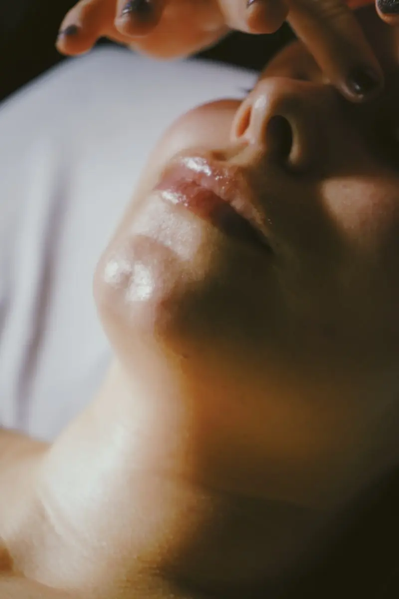 Gros plan sur un soin du visage avec mains effleurant la peau et les lèvres