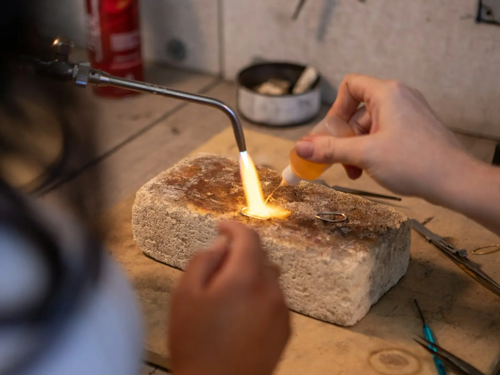 Bijoutier soudant une bague en or au chalumeau sur une brique réfractaire en atelier