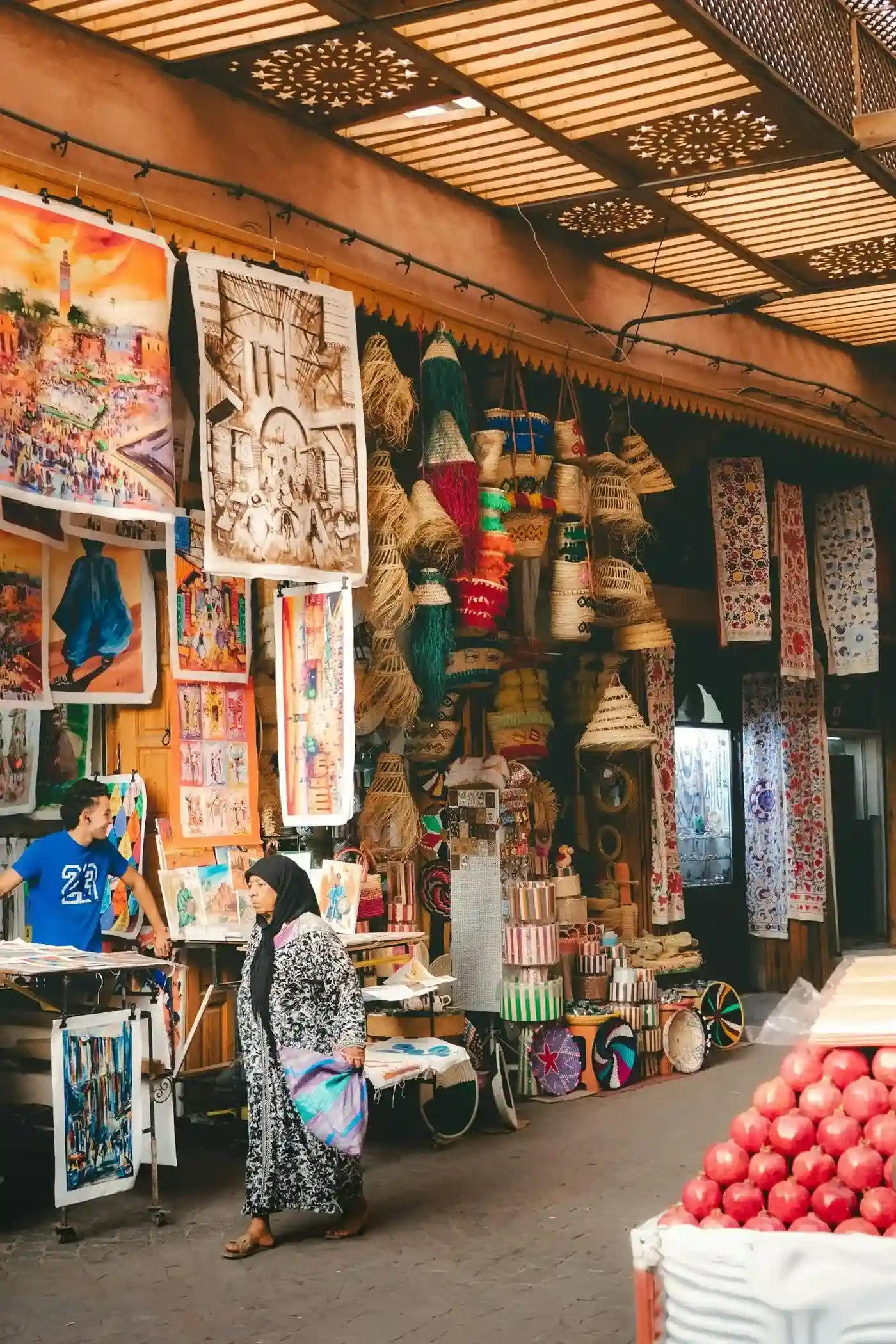 Ruelle de souk artisanal avec paniers tressés, peintures et étoffes brodées exposées en devanture