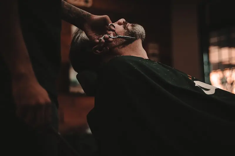 Barbier taillant la barbe d'un client avec des ciseaux de précision