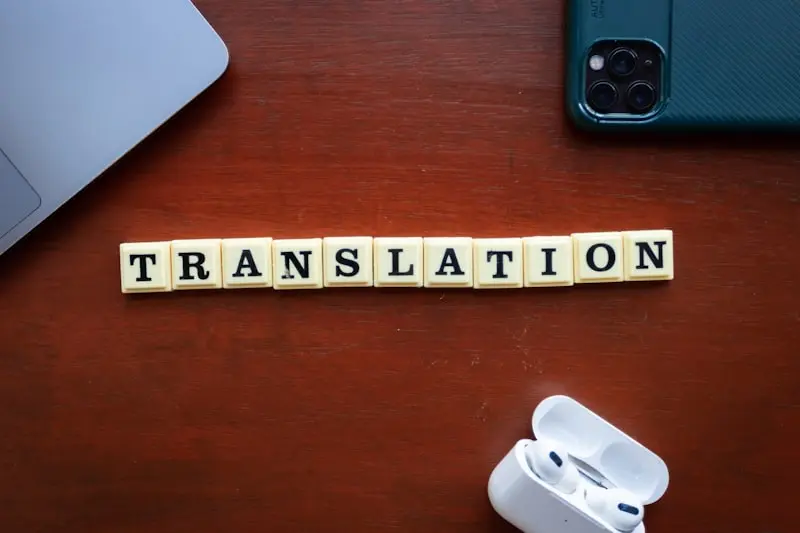 Lettres formant le mot Translation posées sur un bureau avec ordinateur et écouteurs