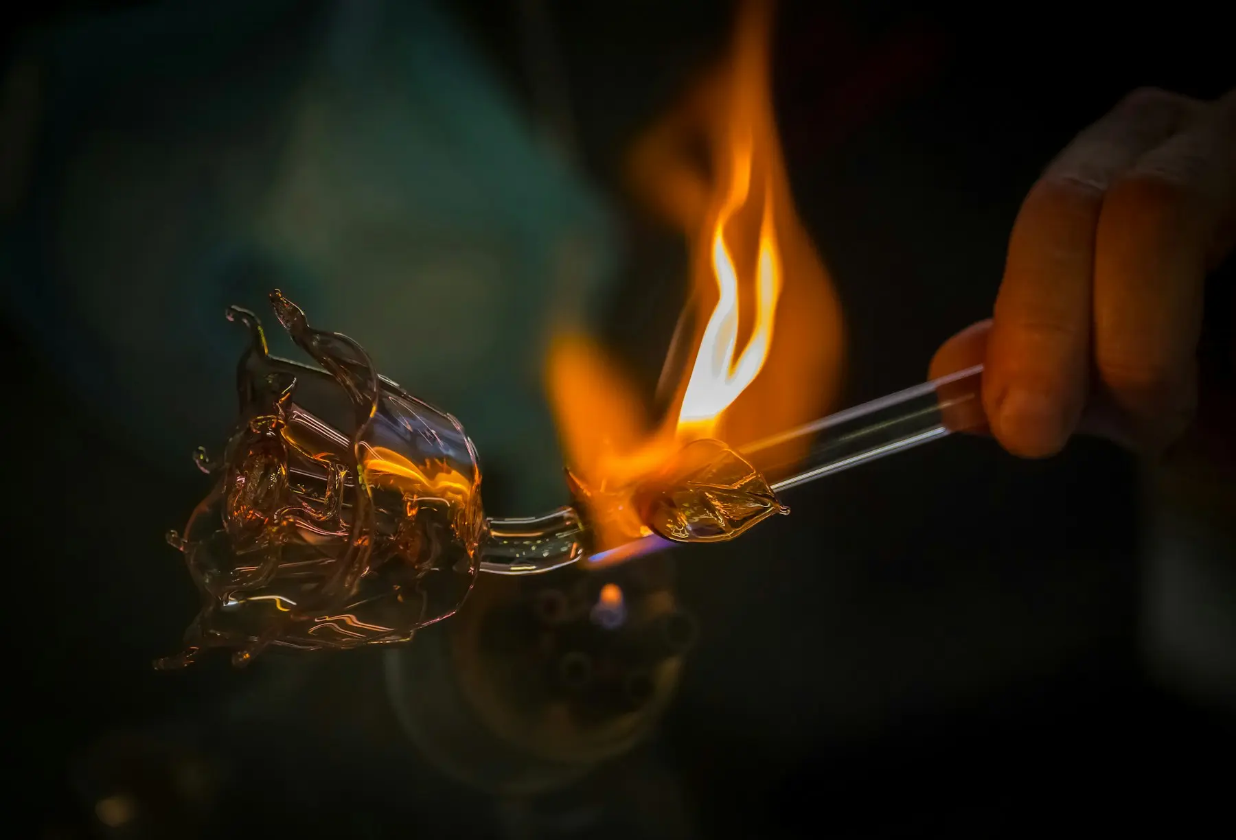 Verrier façonnant une pièce de verre en fusion à la flamme du chalumeau